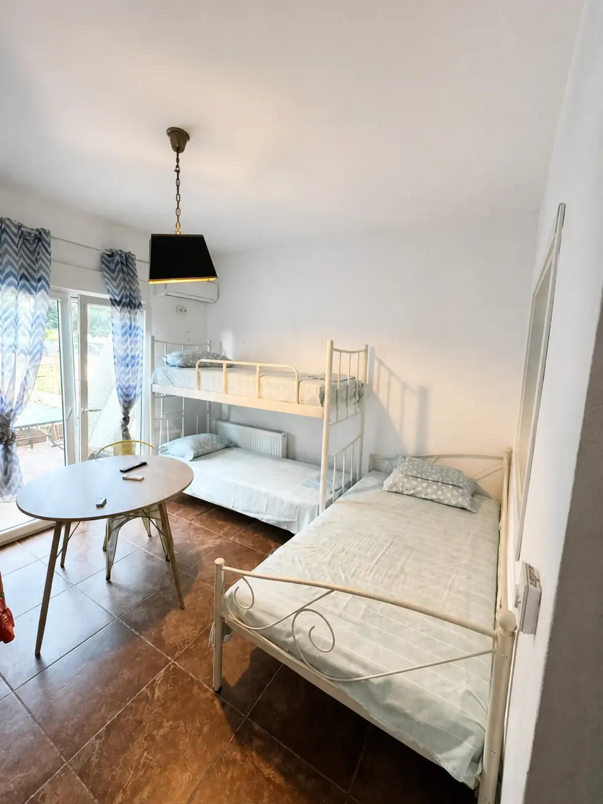 Apartment room with a bunk bed, single beds, air conditioning and a table beside the balcony doors