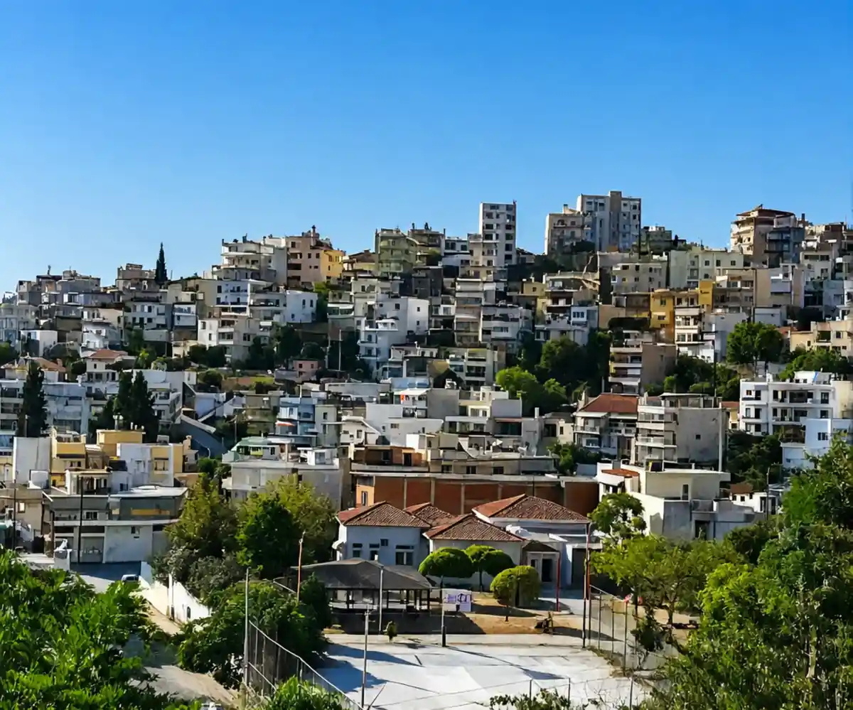 Houses of Néa Karváli rising up the hillside under a clear blue sky